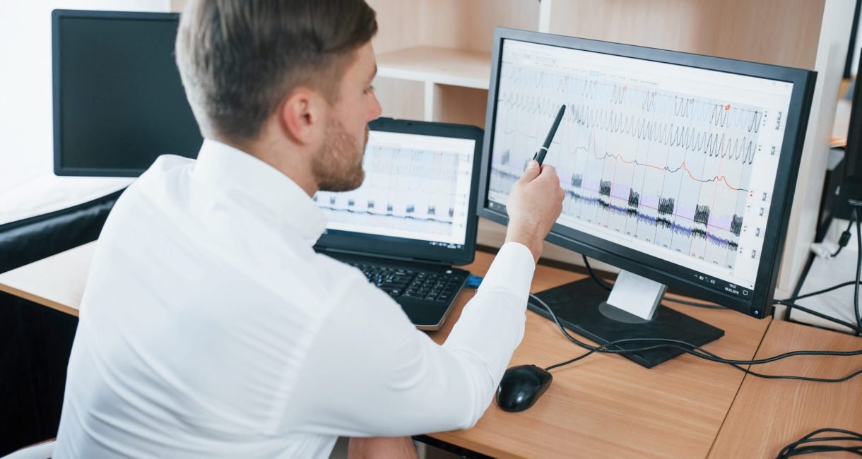 Rear view. Polygraph examiner works in the office with his lie detector's equipment.